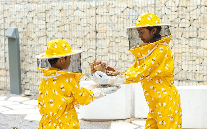 Beekeepers in yellow suits handling hive materials at Terra, Expo City Dubai.