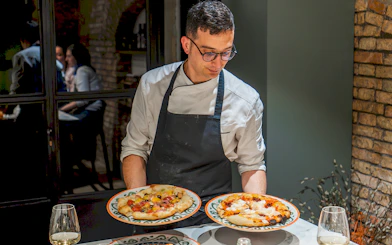 Chef presenting pizzas during a cooking class in Rome.
