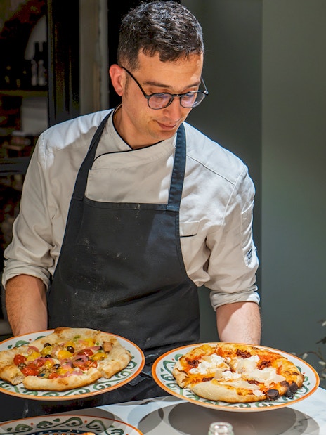 Chef presenting pizzas during a cooking class in Rome.