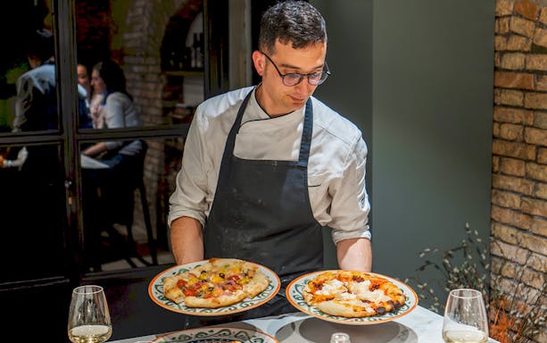 Chef presenting pizzas during a cooking class in Rome.