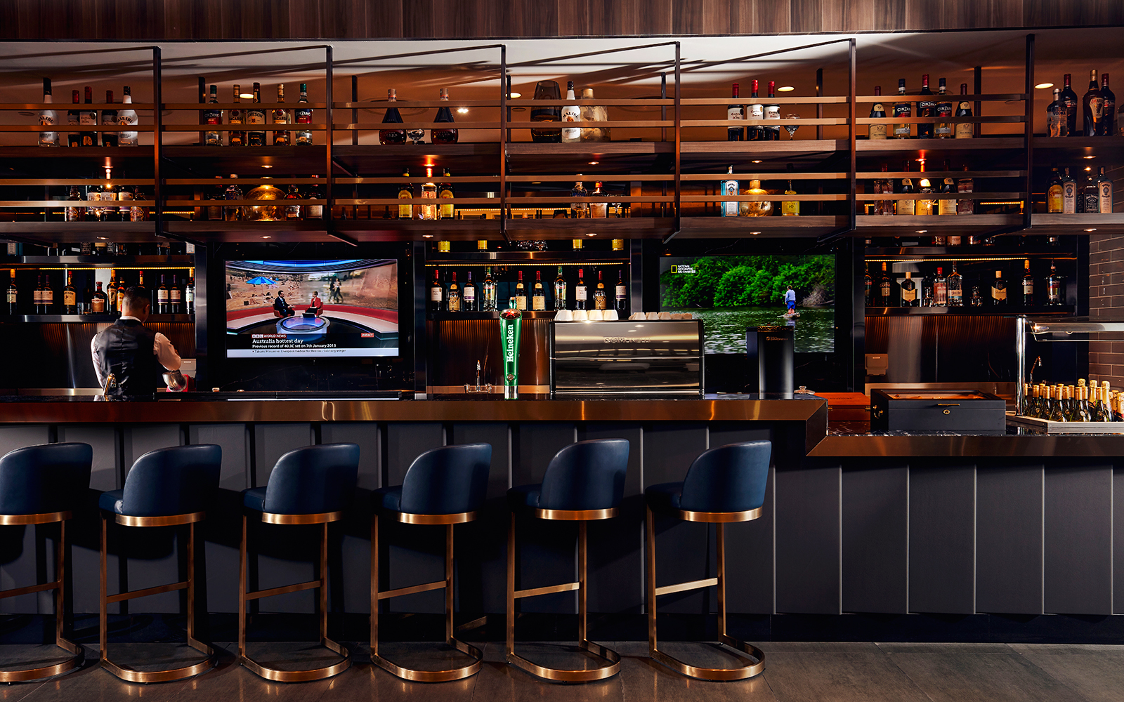 Bar area at Plaza Premium Lounge, Dubai International Airport, with seating and TV screens.