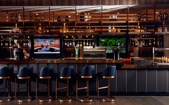 Bar area at Plaza Premium Lounge, Dubai International Airport, with seating and TV screens.