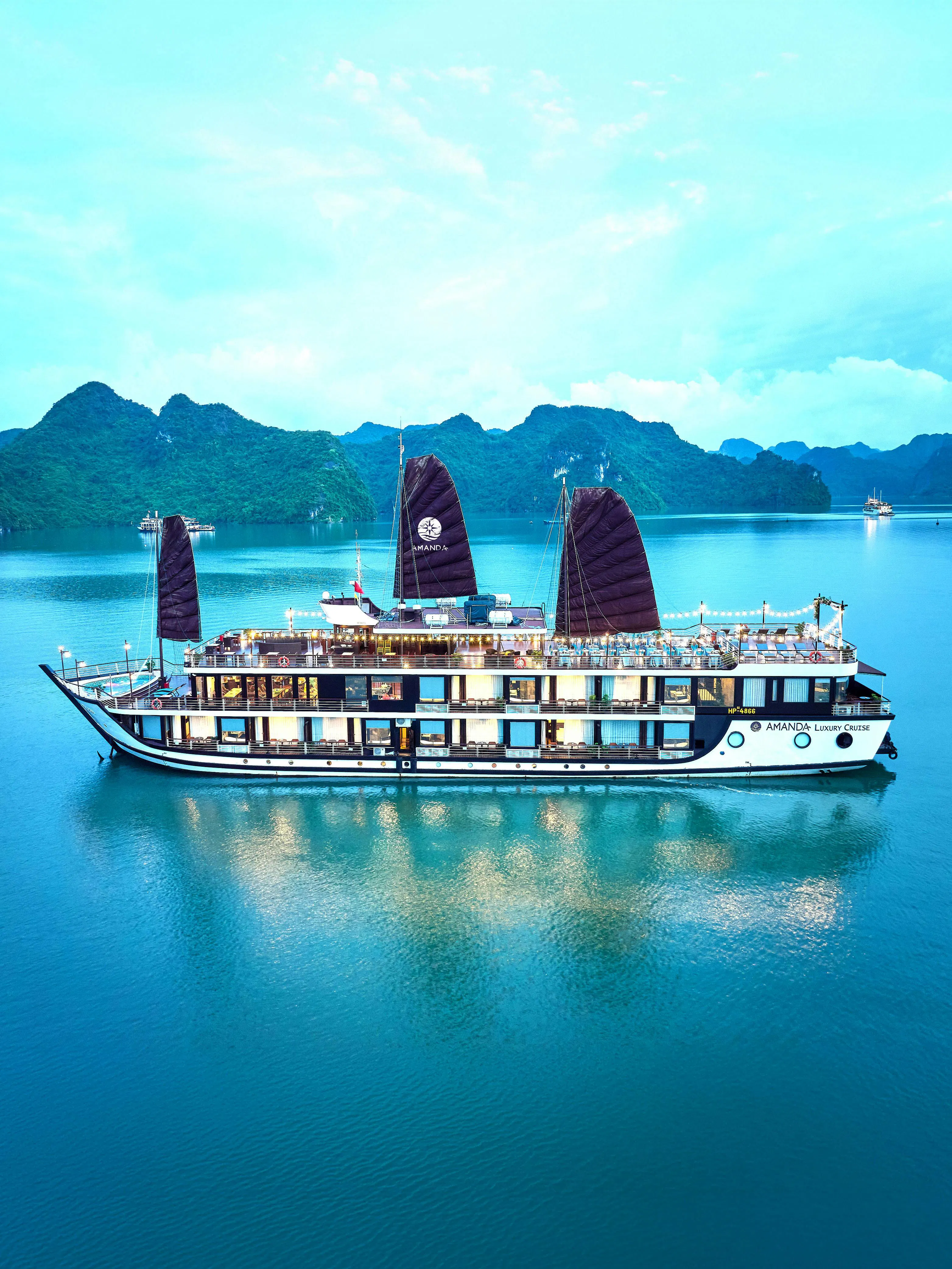 Luxury cruise ship sailing in Halong Bay with limestone karsts in the background.