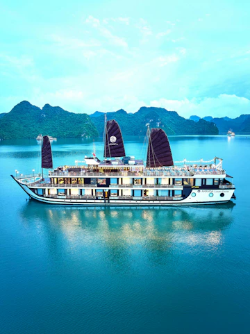 Luxury cruise ship sailing in Halong Bay with limestone karsts in the background.