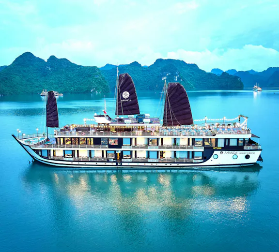 Luxury cruise ship sailing in Halong Bay with limestone karsts in the background.