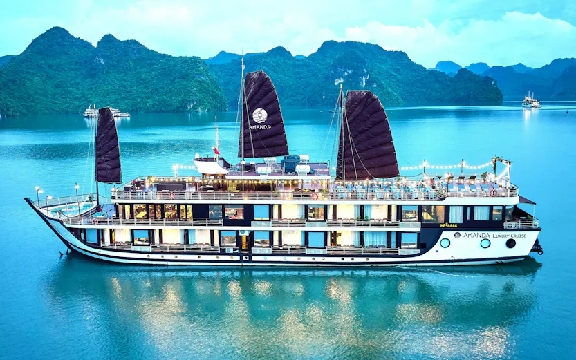 Luxury cruise ship sailing in Halong Bay with limestone karsts in the background.