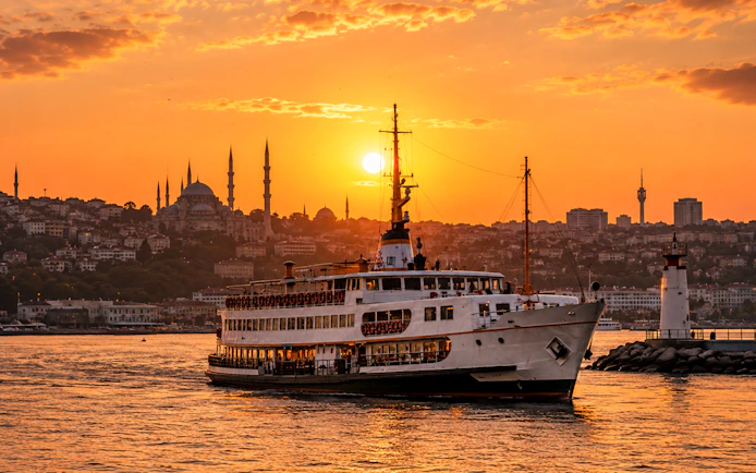 Ferry sailing near Galata Tower at sunset in Istanbul.