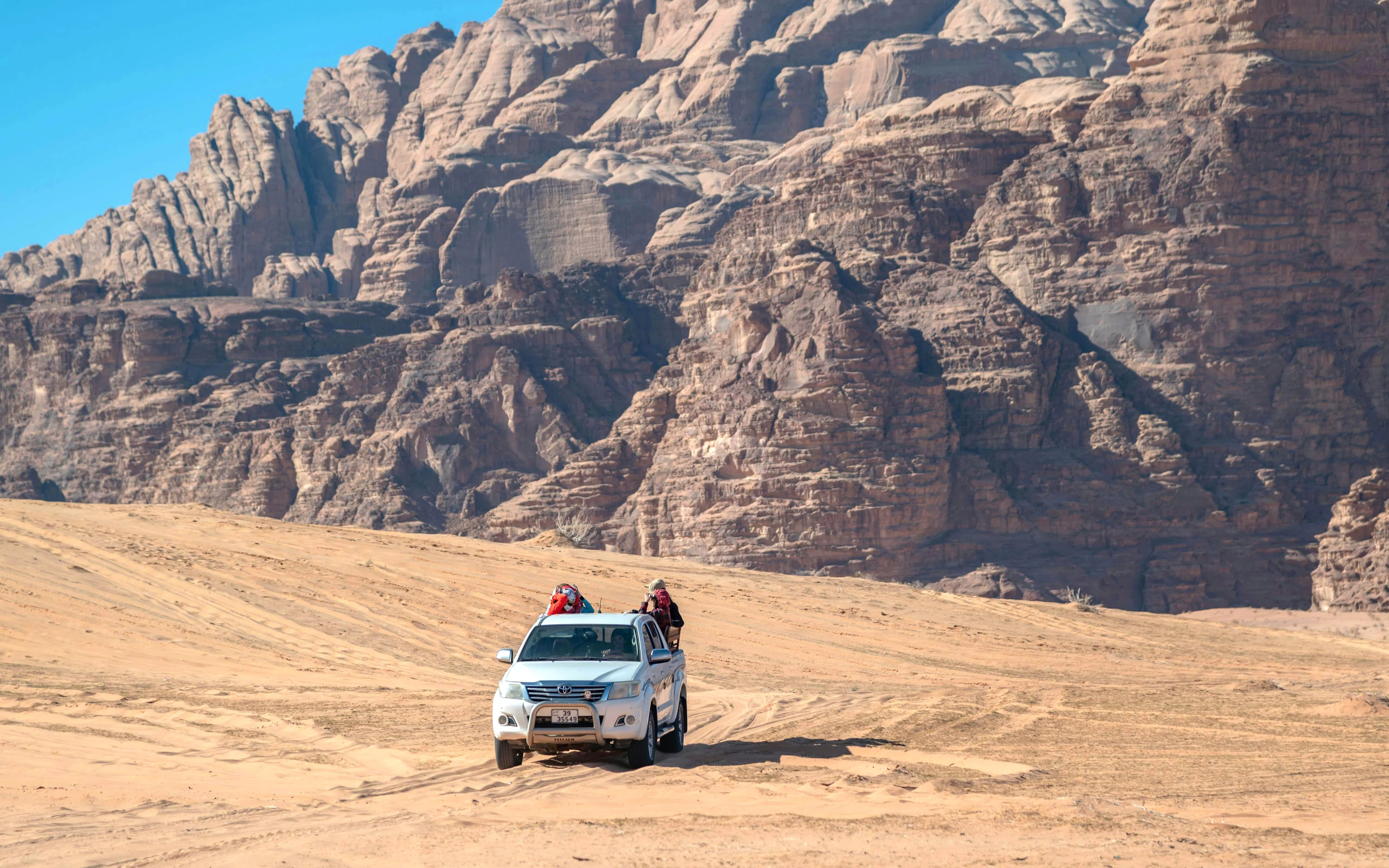 4x4 vehicle driving through Wadi Rum desert landscape.