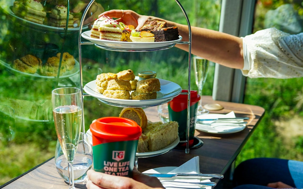 Afternoon tea with pastries and scones on a bus tour, featuring tea and champagne.