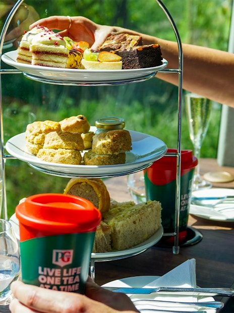 Afternoon tea with pastries and scones on a bus tour, featuring tea and champagne.