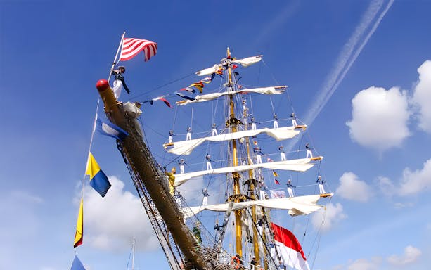 Tall ship with sailors on masts during Sail Amsterdam event.