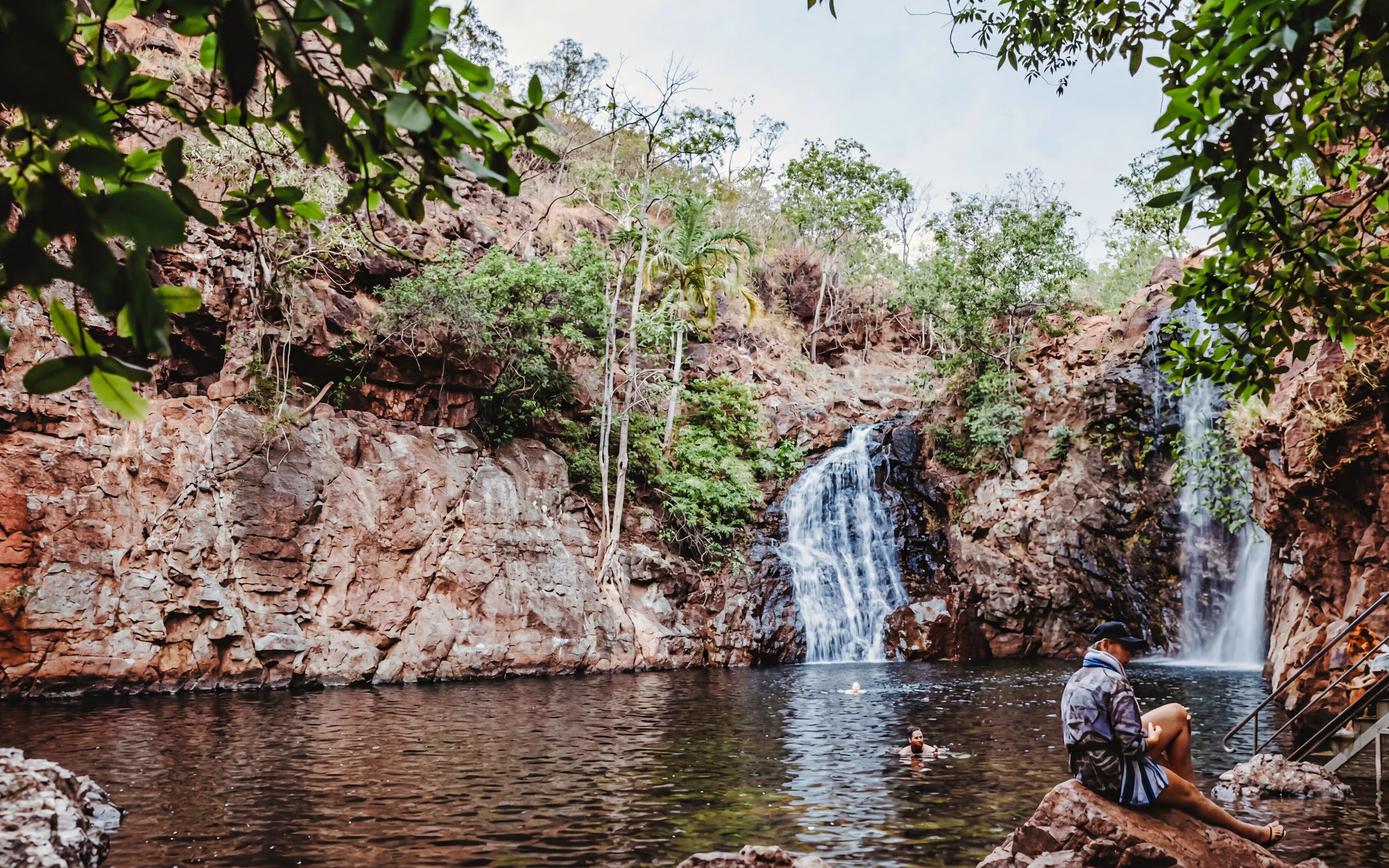 Waterfall and swimming area in Litchfield National Park, Australia, with visitors enjoying the water.