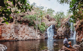 Waterfall and swimming area in Litchfield National Park, Australia, with visitors enjoying the water.