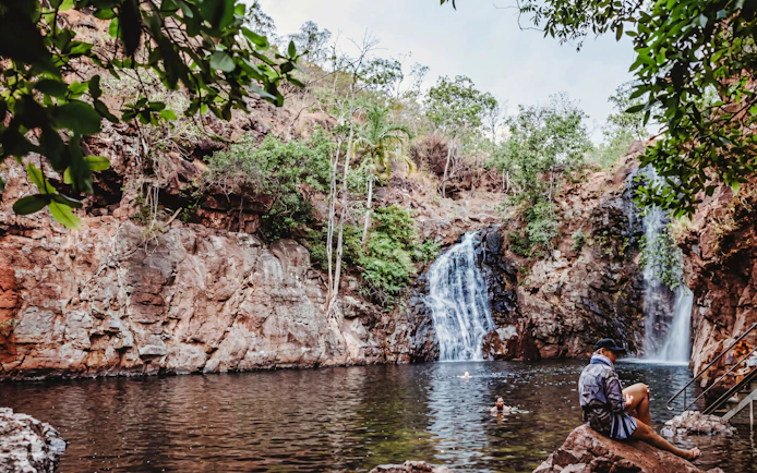 Waterfall and swimming area in Litchfield National Park, Australia, with visitors enjoying the water.