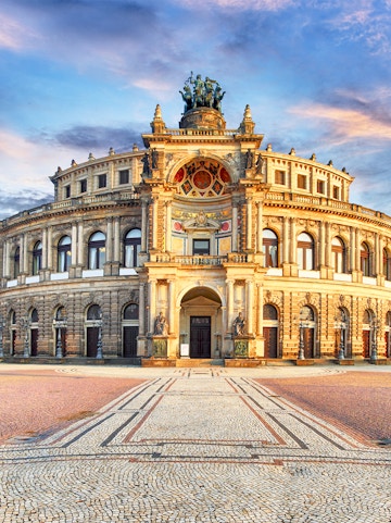 Semperoper Dresden exterior with ornate architecture and statues at sunset.