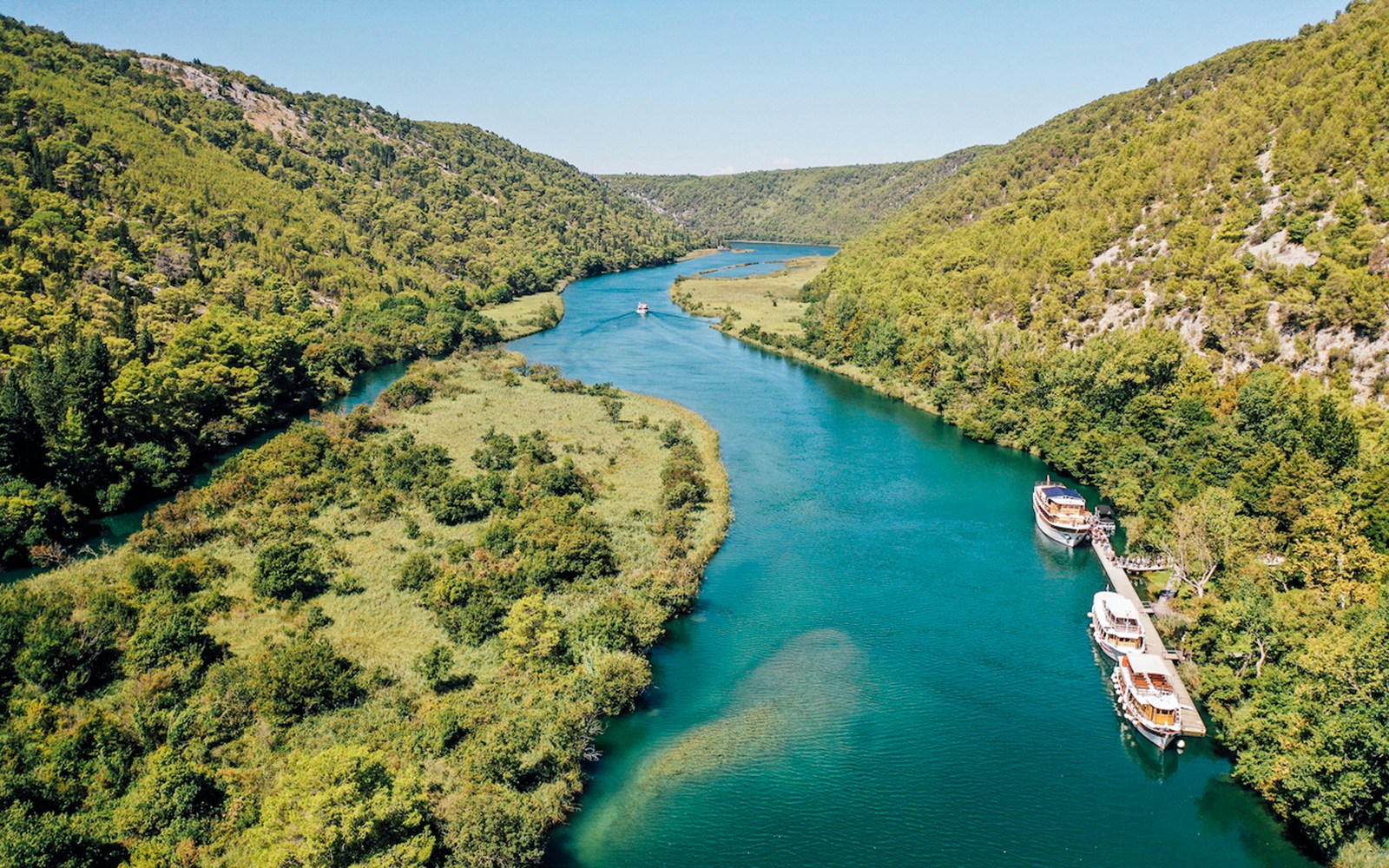 Boat on Krka River surrounded by lush greenery in Krka National Park, Croatia.