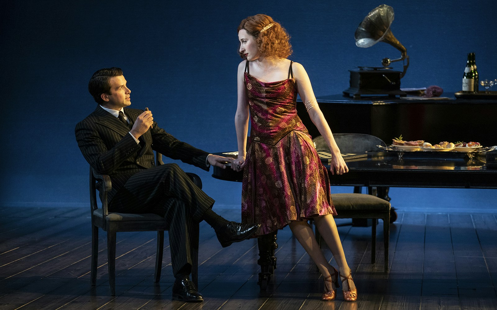 Man and woman in 1920s attire in a Leopoldstadt theater scene with gramophone and dining table.