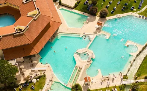 Thermal park pools with visitors swimming, surrounded by greenery, Ingresso giornaliero al Parco Termale.