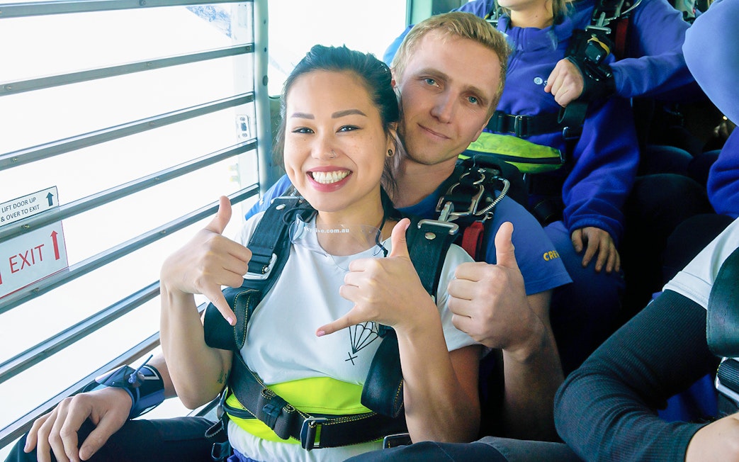Tandem skydivers giving thumbs up before jumping over St Kilda Beach, Melbourne.