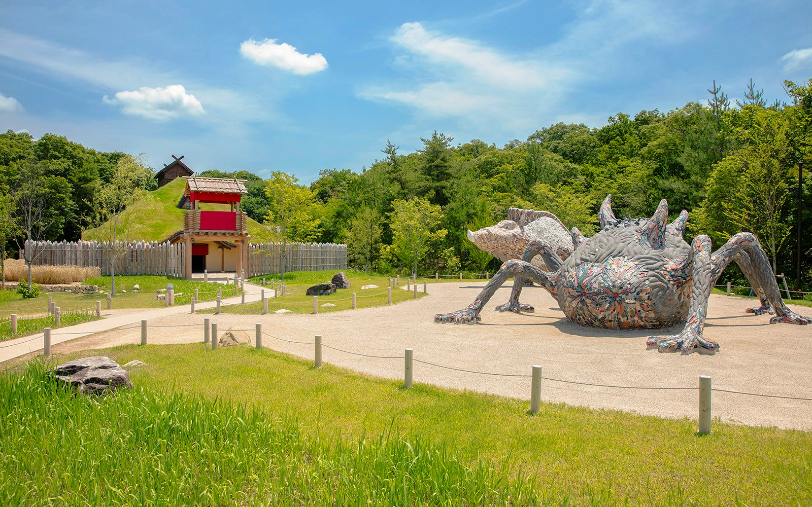 Giant creature sculpture at Ghibli Park's Mononoke Village, surrounded by greenery and traditional architecture.