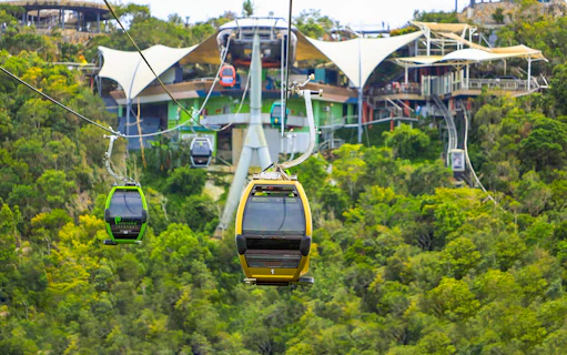 Langkawi SkyCab cable cars ascending over lush green hills toward the station.