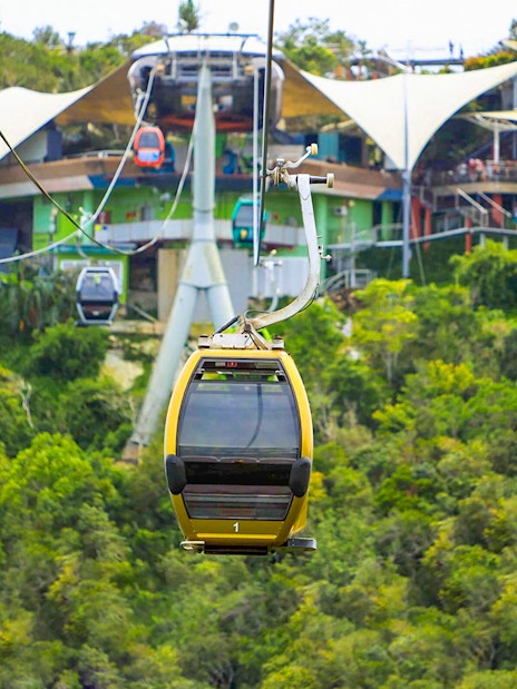 Langkawi SkyCab cable cars ascending over lush green hills toward the station.