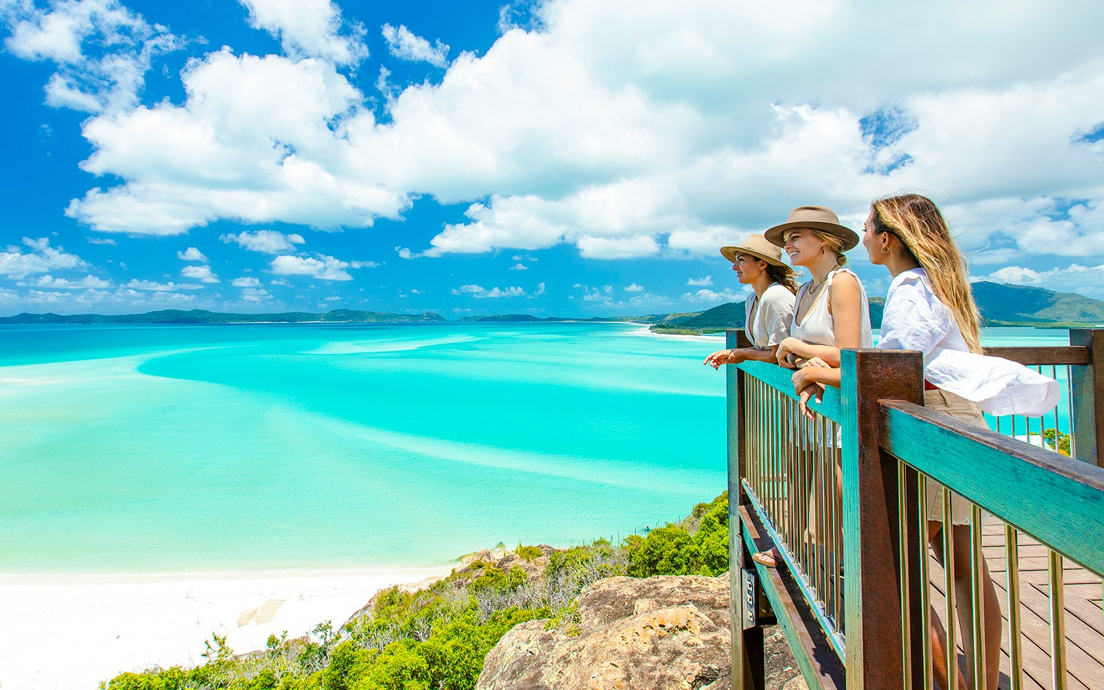 Tourists enjoying the view from Hill Inlet Lookout, Whitsundays, overlooking turquoise waters.
