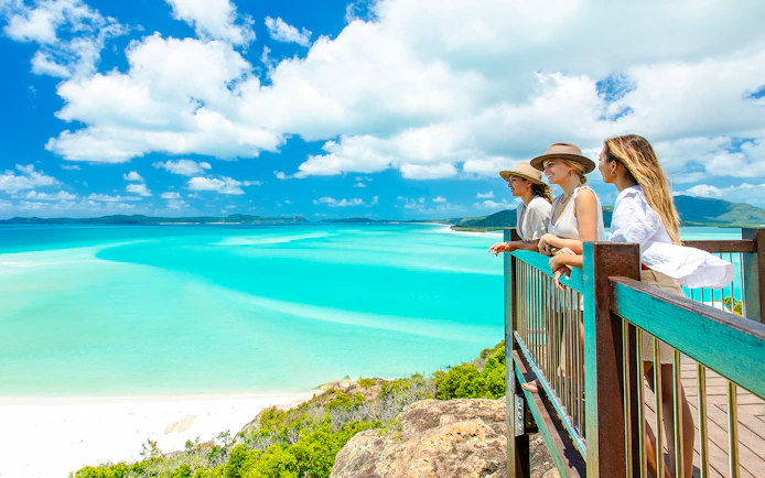 Tourists enjoying the view from Hill Inlet Lookout, Whitsundays, overlooking turquoise waters.