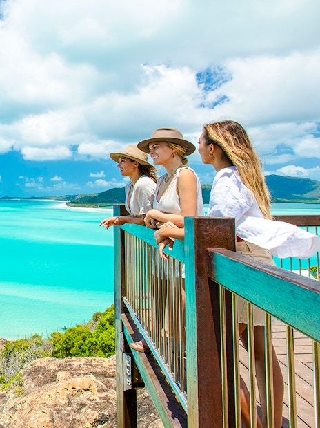 Tourists enjoying the view from Hill Inlet Lookout, Whitsundays, overlooking turquoise waters.