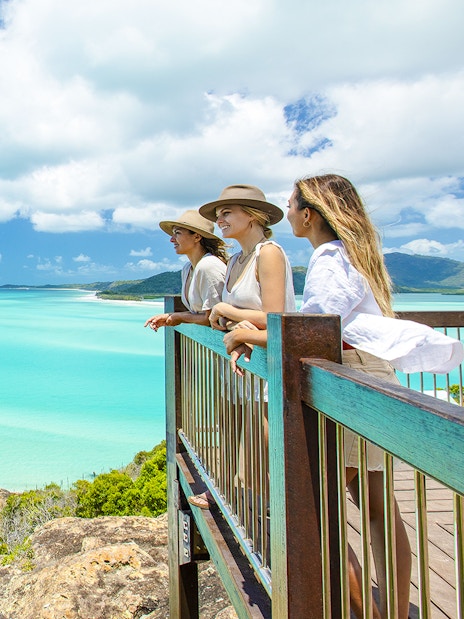 Tourists enjoying the view from Hill Inlet Lookout, Whitsundays, overlooking turquoise waters.