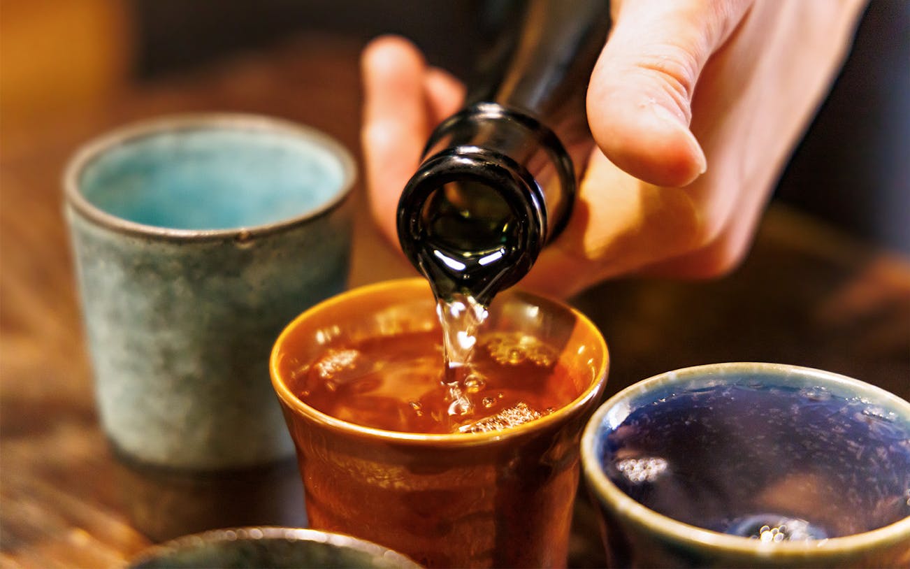 Pouring sake into a ceramic cup at Seibu Ikebukuro tasting event.