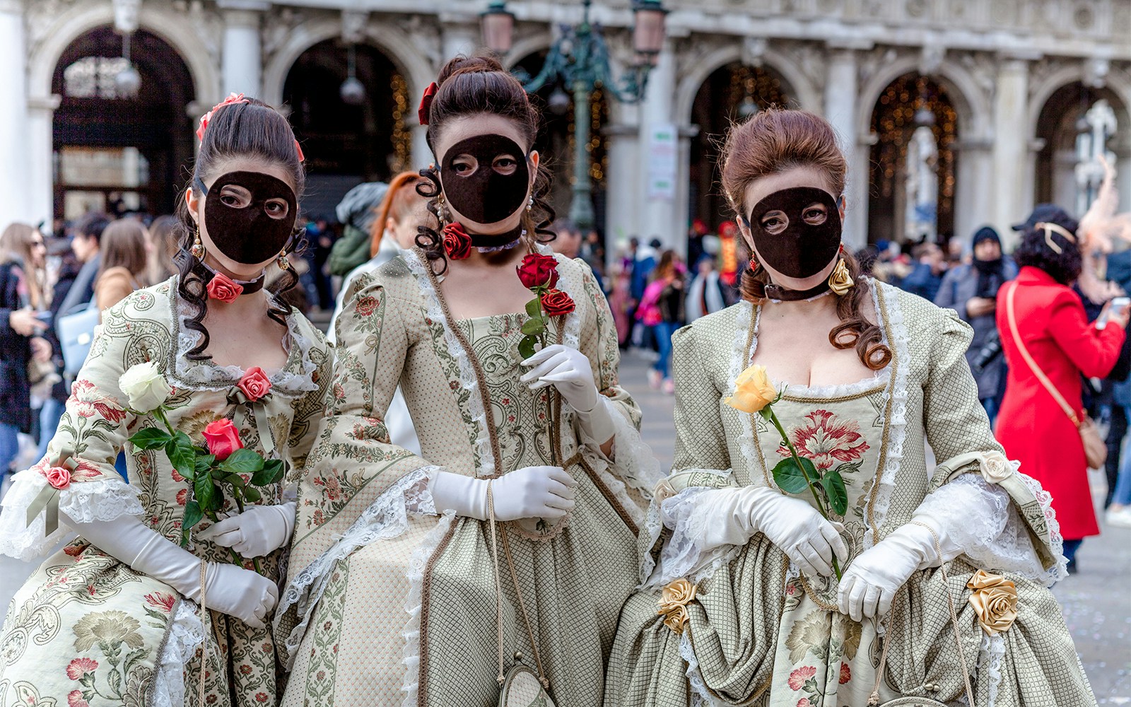 Venice Carnival attendees wearing traditional Moretta masks in a vibrant street celebration.