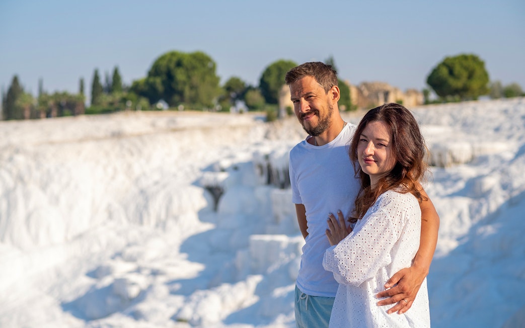 Couple admiring Pamukkale's white terraces under clear skies.