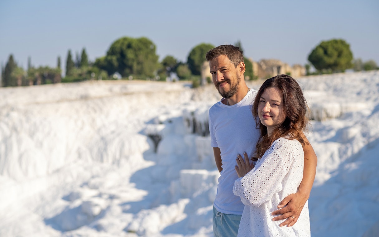 Couple admiring Pamukkale's white terraces under clear skies.