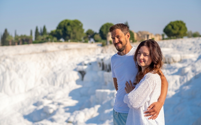 Couple admiring Pamukkale's white terraces under clear skies.