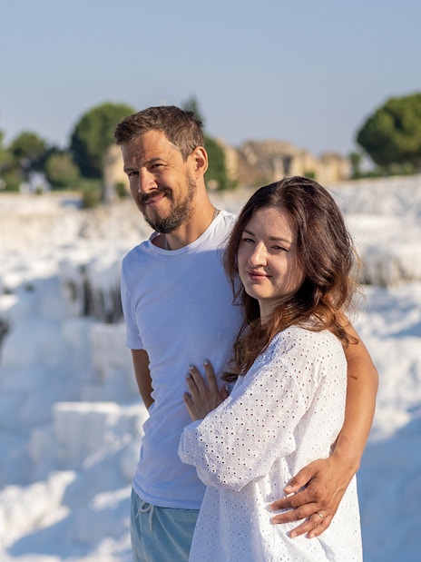 Couple admiring Pamukkale's white terraces under clear skies.