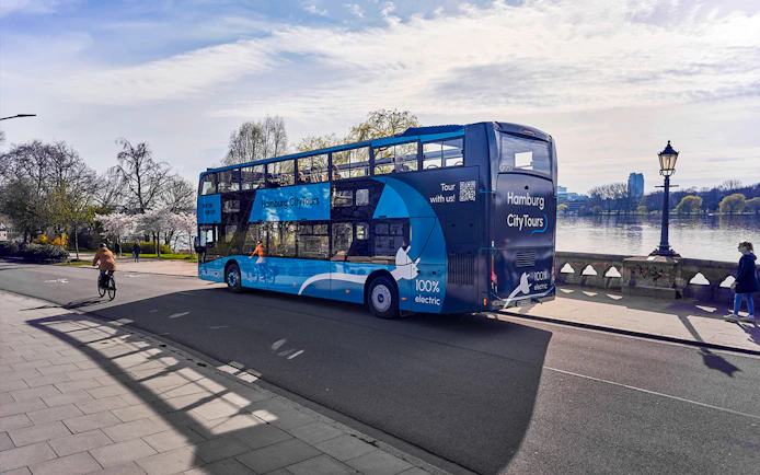 Electric double-decker bus on Hamburg city tour near Alster Lake.