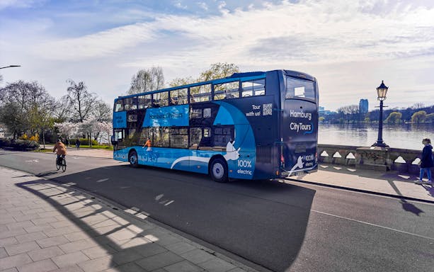 Electric double-decker bus on Hamburg city tour near Alster Lake.