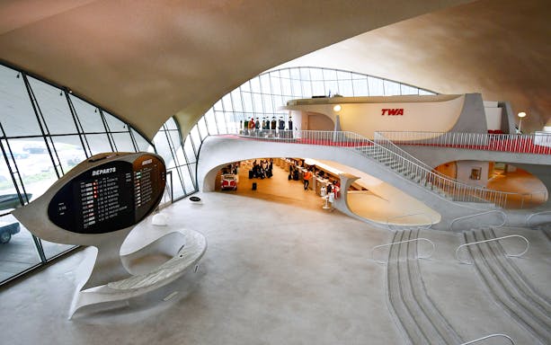 TWA terminal interior at JFK Airport, showcasing retro design and flight information board.