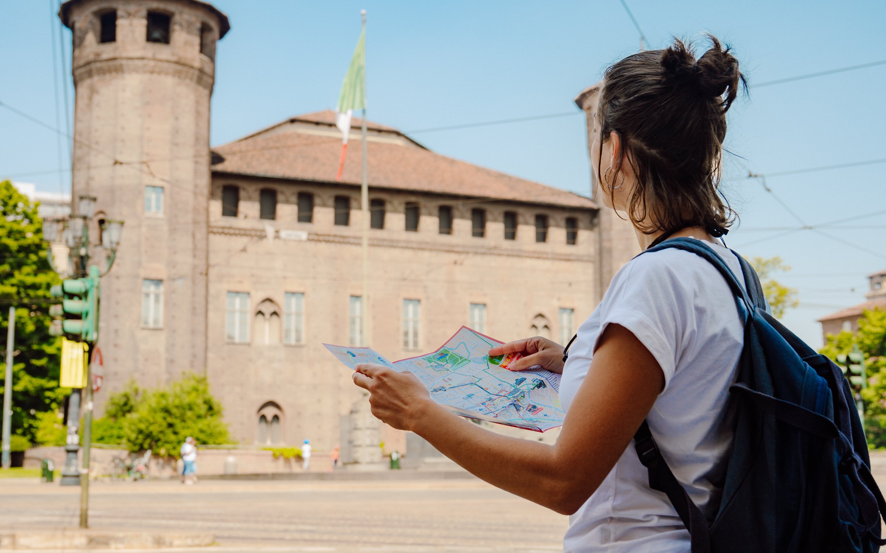 Tourist with map near historic building on Turin hop-on hop-off bus tour.