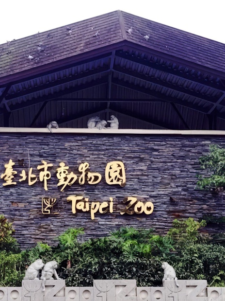 Taipei Zoo entrance sign with stone wall and greenery.