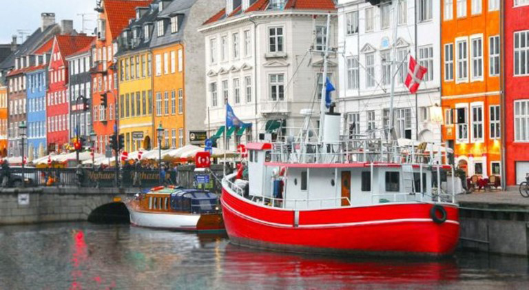 Colorful houses and a red boat in Nyhavn, Copenhagen canal cruise view.