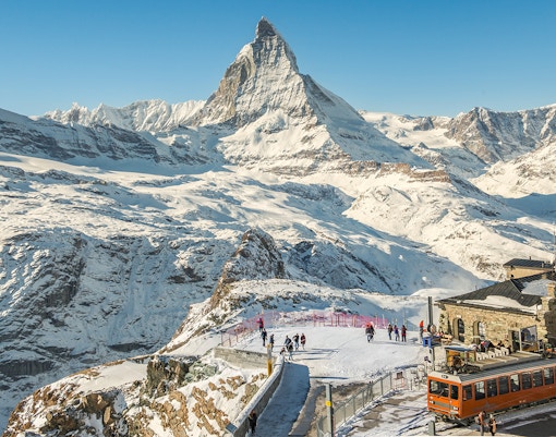 Scenic view of the Matterhorn with a train and skiers in Zermatt, Switzerland.