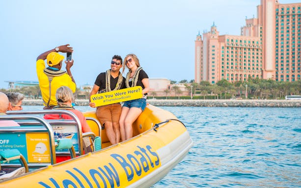 Couple on Dubai speedboat tour with Atlantis hotel in background.