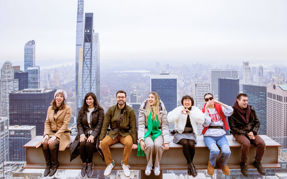 Visitors enjoying the view from Top of the Rock, New York City skyline in background.