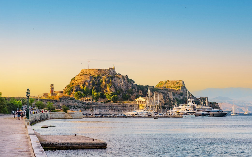 Yachts docked at Garitsa Bay with Corfu's old fortress in the background, Corfu Island, Greece.
