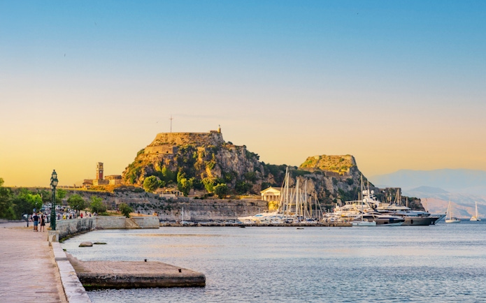 Yachts docked at Garitsa Bay with Corfu's old fortress in the background, Corfu Island, Greece.