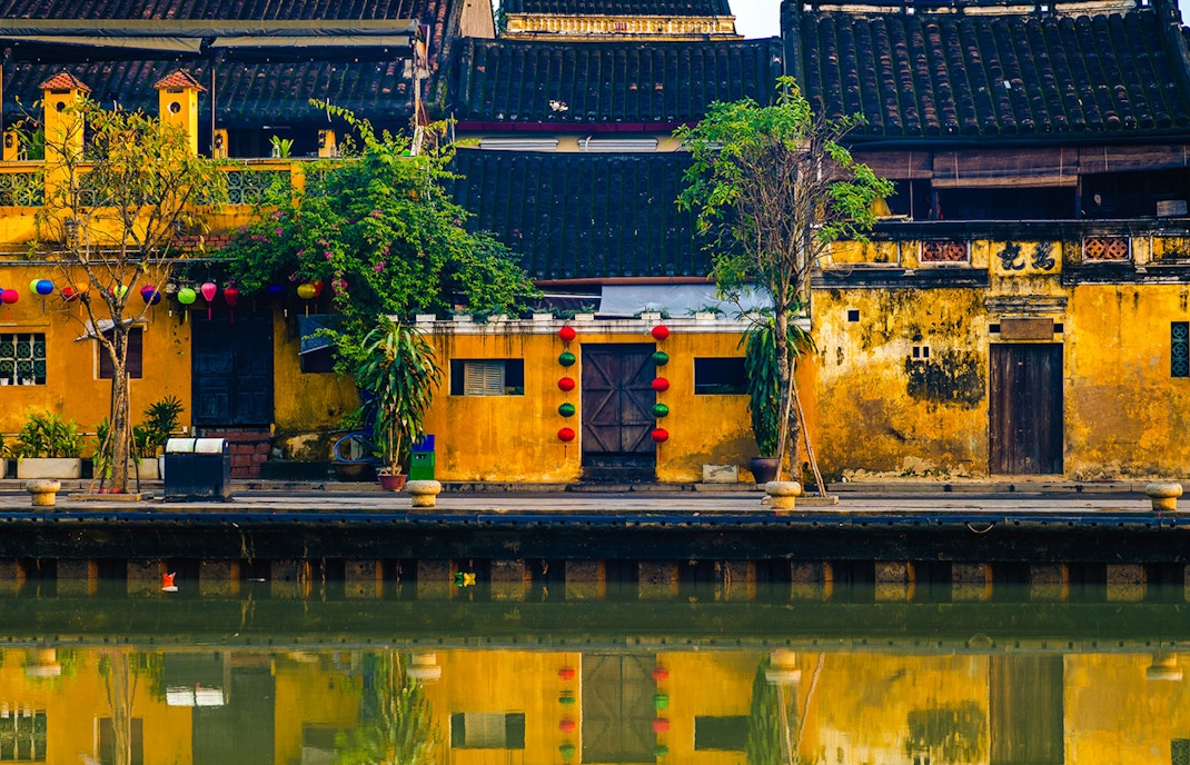 Tan Ky House in Hoi An with yellow facade and colorful lanterns reflected in the water.