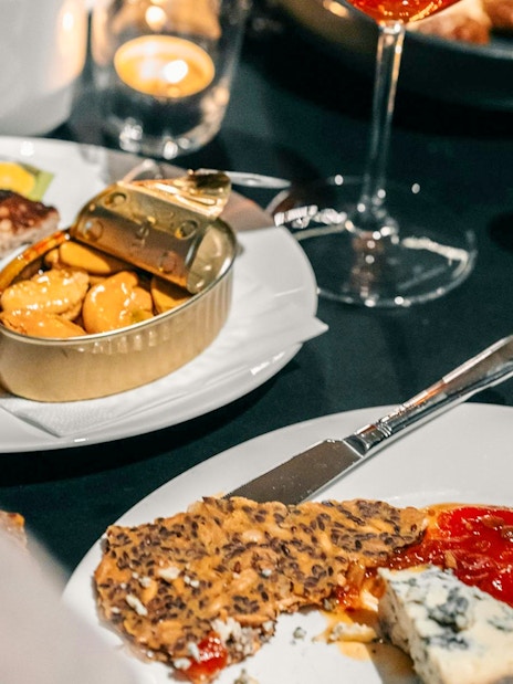 Dining experience at Nobel Prize Museum with cheese, crackers, and canned seafood.