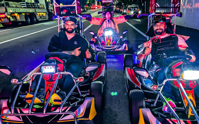 People driving go-karts on a street in Ginza at night.